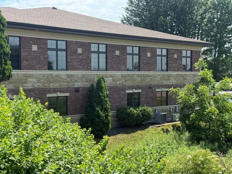 Two-story brick and stone office building with tall windows and mature landscaping, Royal Oaks Business Center at 4410 Golf Ter, Eau Claire, Wisconsin