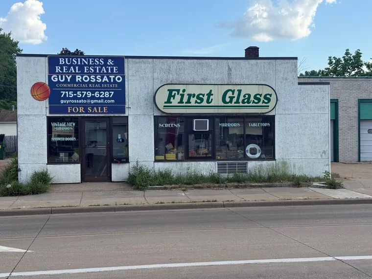 Single-story white freestanding commercial building with storefront windows on a city street at 2209 Birch St, Eau Claire, Wisconsin