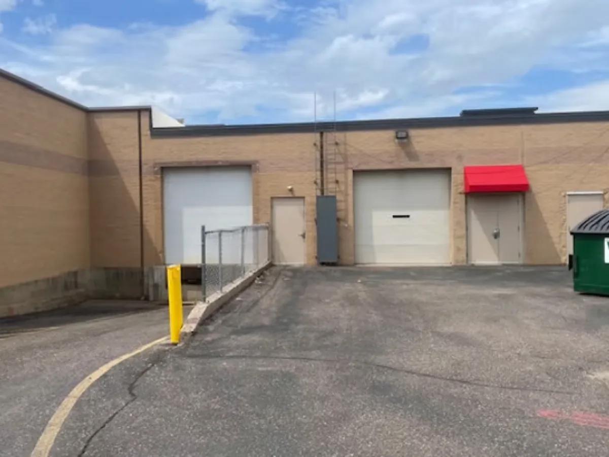 Tan brick warehouse with two overhead loading doors and a paved loading area at 875 W Clairemont Ave, Eau Claire, Wisconsin